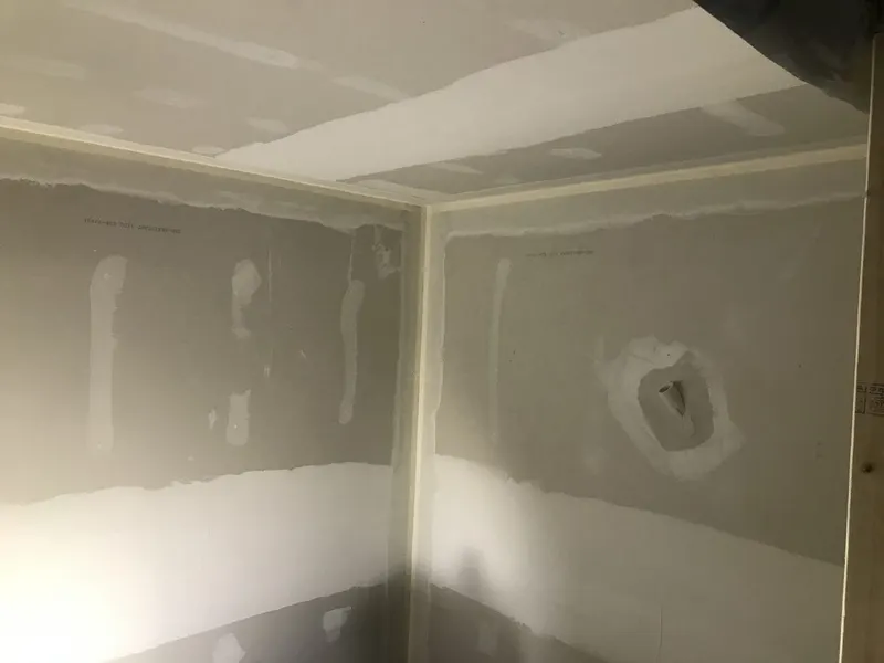 Drywall seams and a hole patch mudded in a room corner, ready for sanding