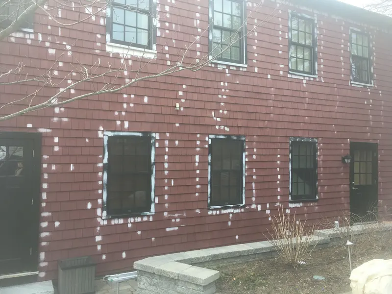 Two-story house siding spot-patched before exterior paint