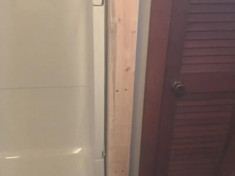 Finished bathroom walls beside a louvered door