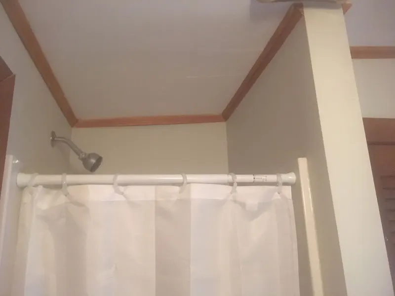 Finished bathroom with fresh paint and wood trim around the shower