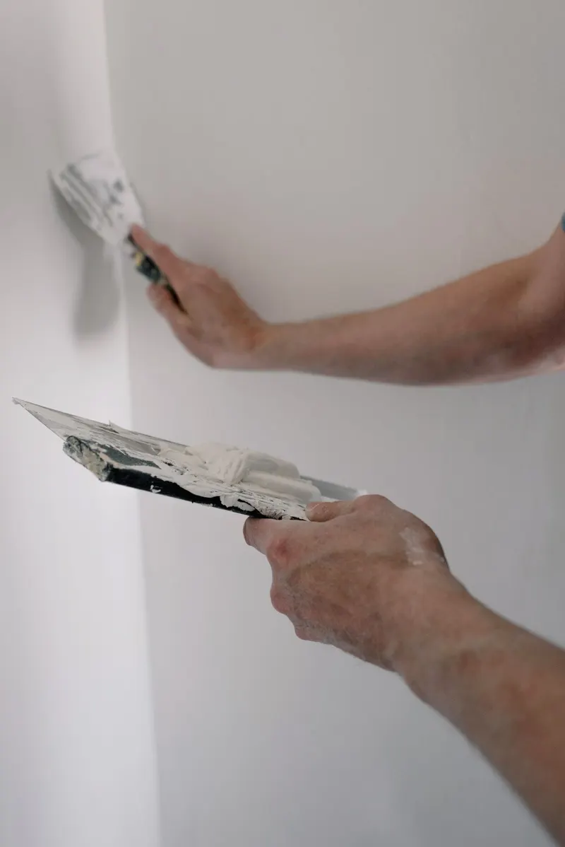 Applying joint compound with putty knives during wall finishing